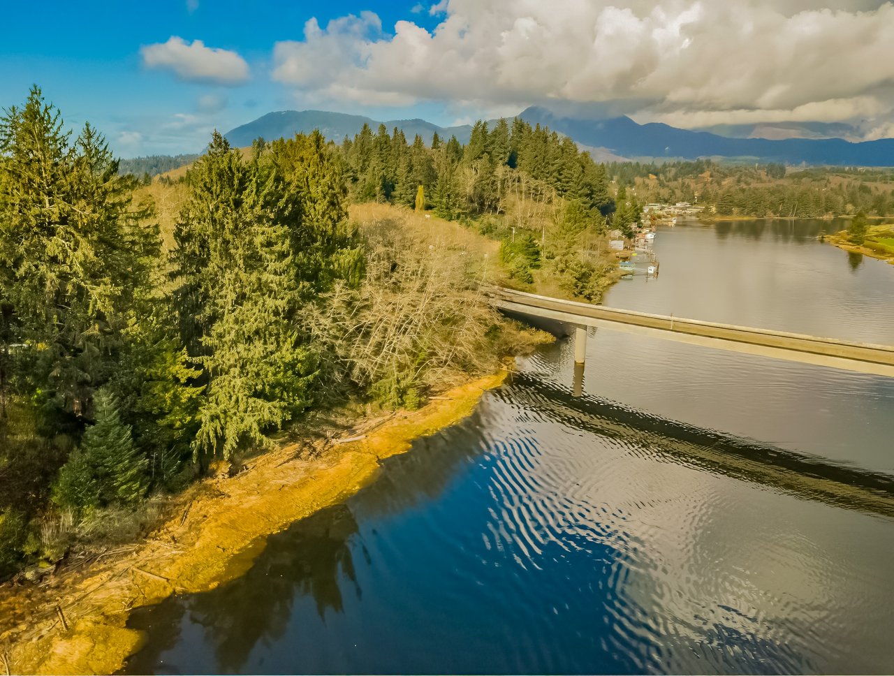 Sold wooded land parcel at Riverway Dr VL 10 in Nehalem, Oregon, represented by Erin Laskey of Home + Sea Realty, with gated access and water frontage noted in the listing.