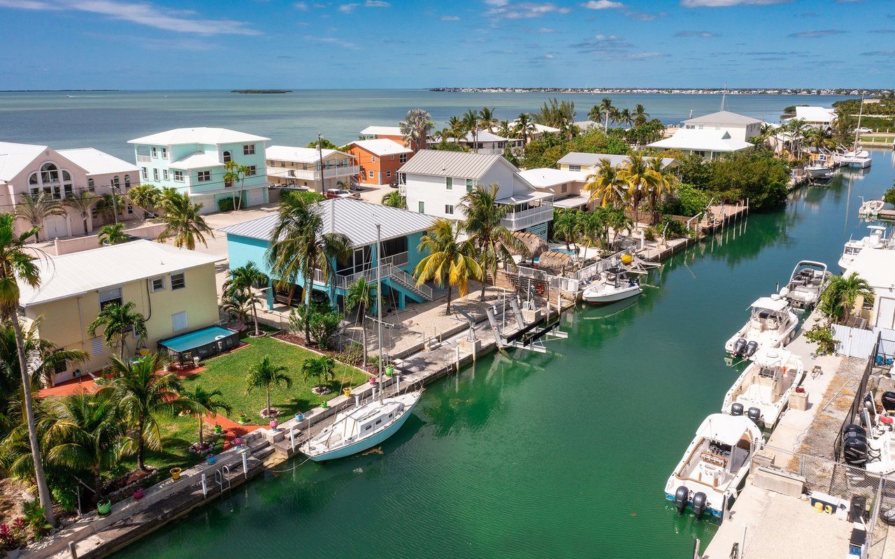 Aerial view of colorful waterfront homes and boats along a canal in Summerland Key.