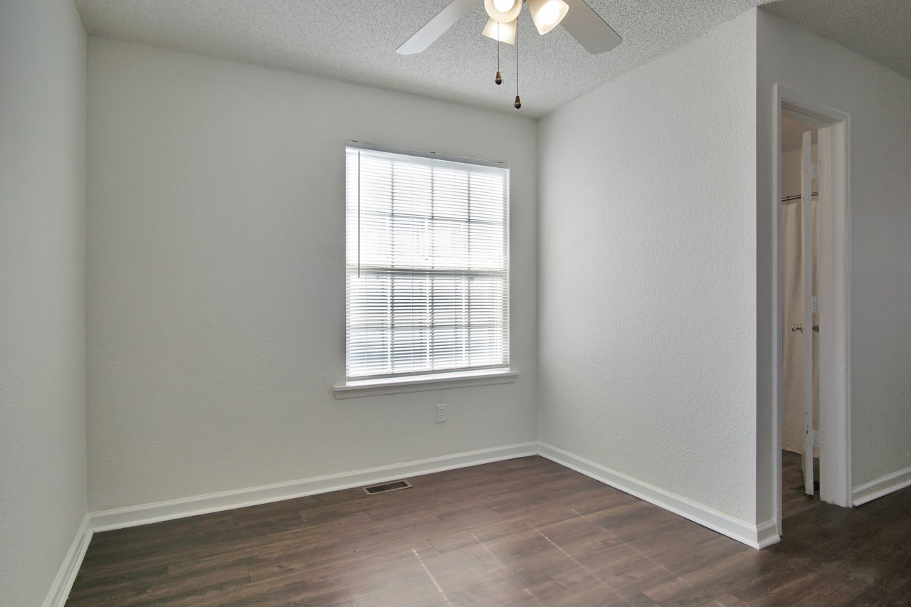 Empty room featuring hardwood floors and a ceiling fan, creating a spacious and airy atmosphere.