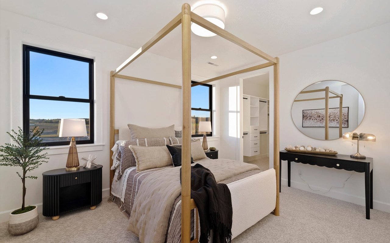 Upstairs bedroom featuring two black steel windows and a wood four-poster bed