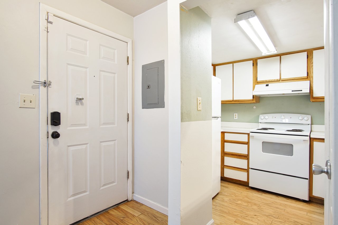 A bright kitchen featuring a white stove and a door, showcasing a clean and modern design.