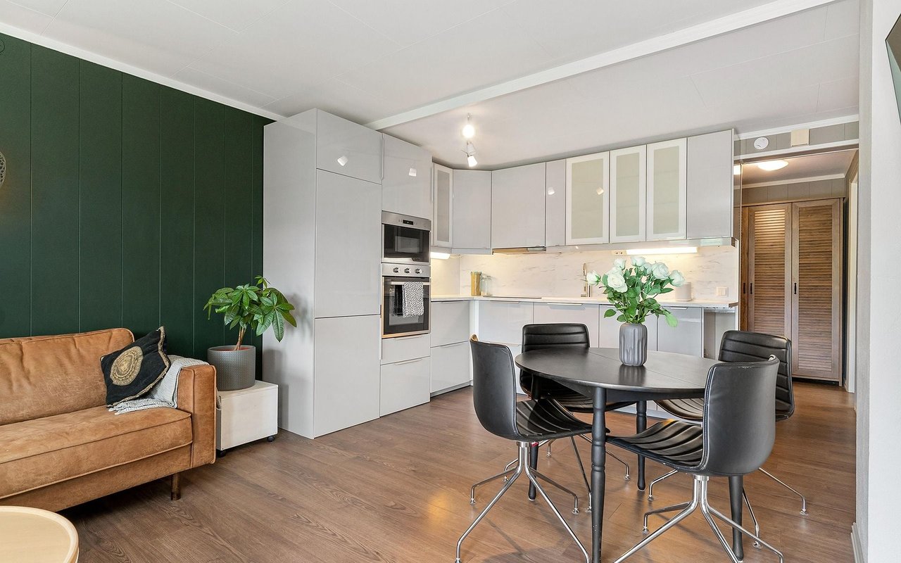 Open-plan kitchen and dining area with white cabinets and a deep green accent wall.