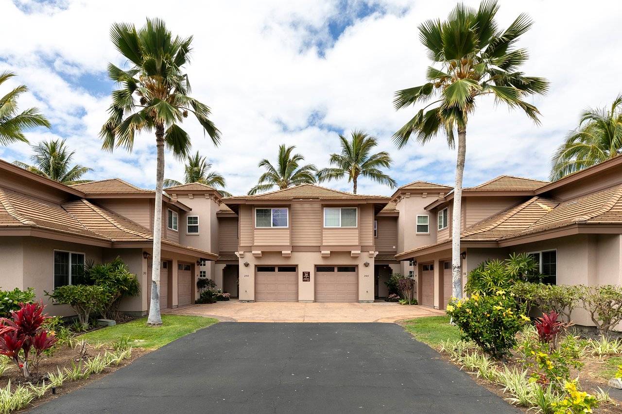 Multi-unit residence with tan tiled roofs, central garages, tropical landscaping, and tall palm trees.