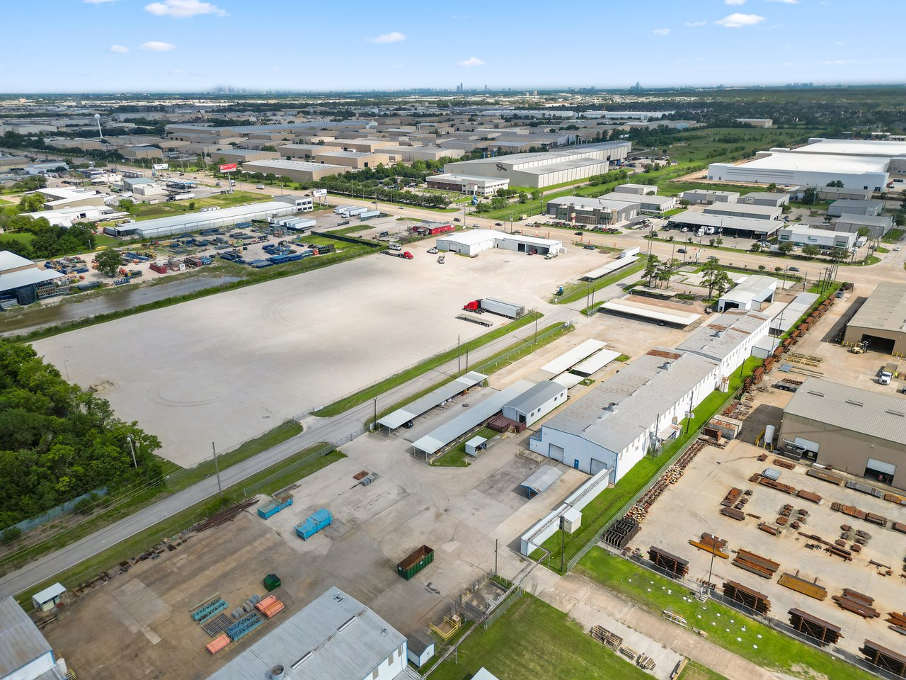 Aerial view of warehouse and office buildings with a broad paved yard in an industrial district.