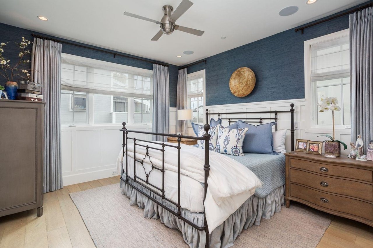  A modern bedroom with a black metal bed frame, blue textured wallpaper, and light wood floors.