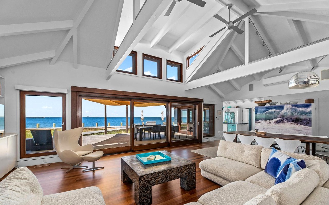 Living room with vaulted beams, expansive windows, and ocean views.