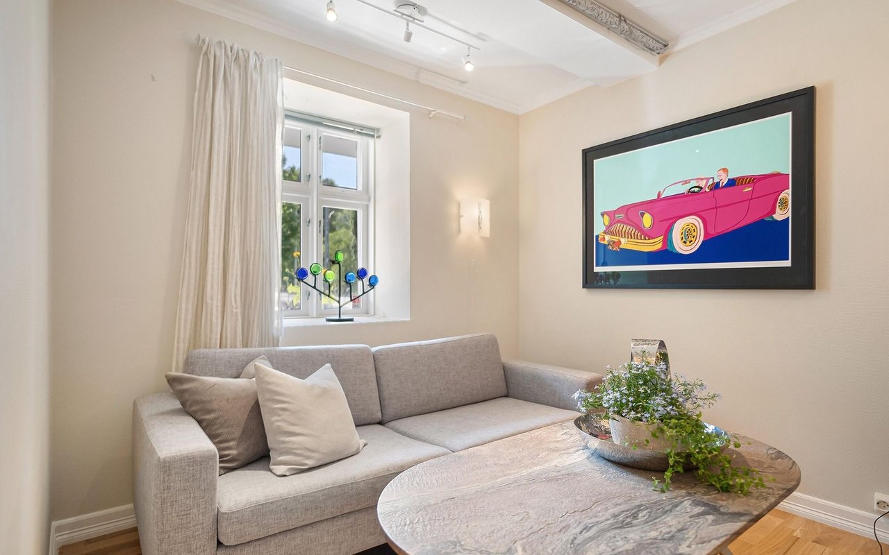 Living room with a gray sofa, marble coffee table, and framed pink vintage car artwork.