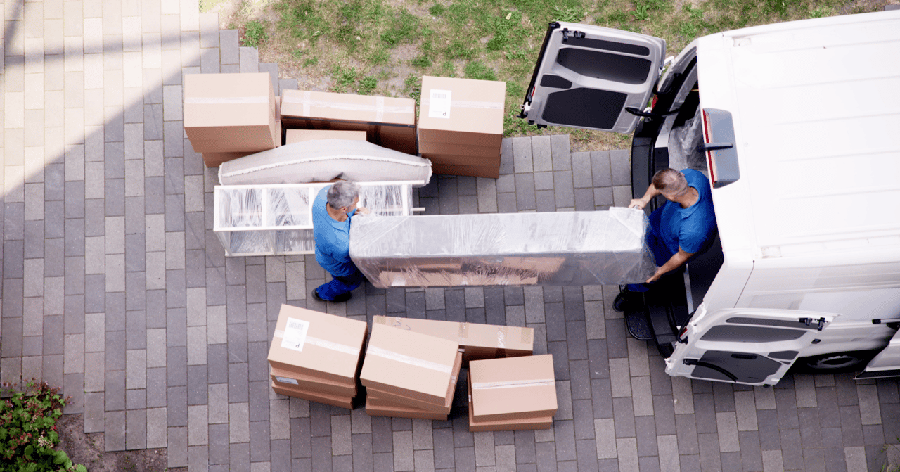 Moving truck unloading furniture and boxes outside a new home during relocation