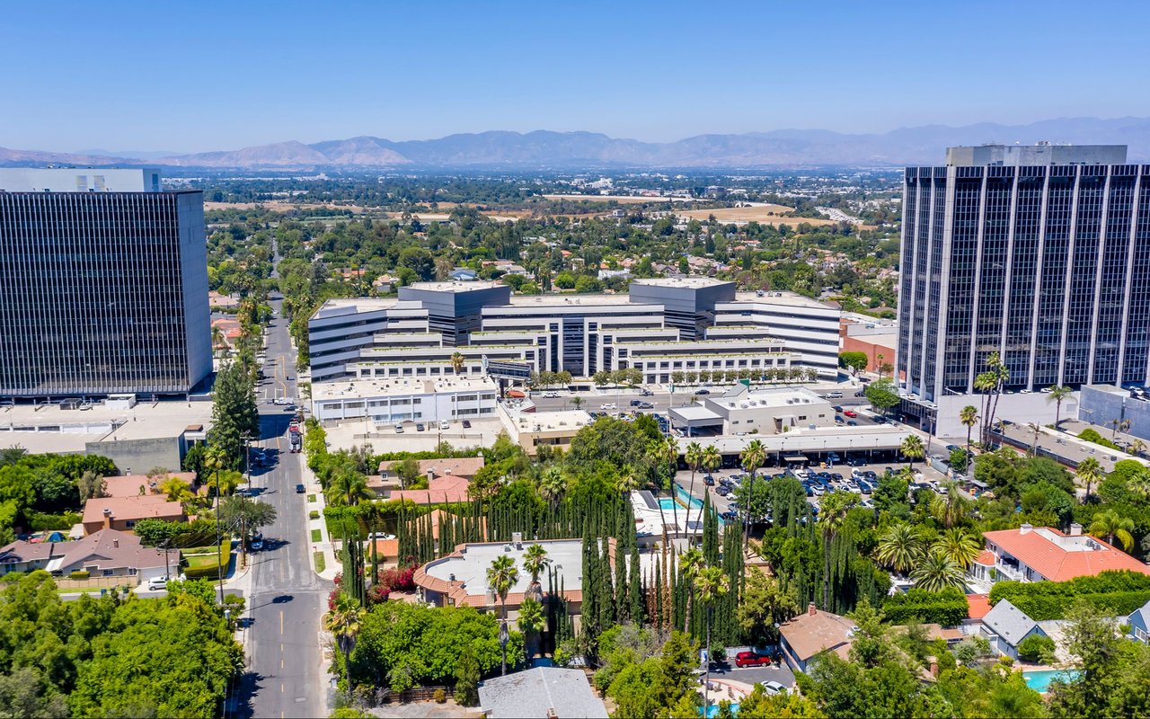 Aerial view of Encino with office towers, homes, and mountains in the distance.