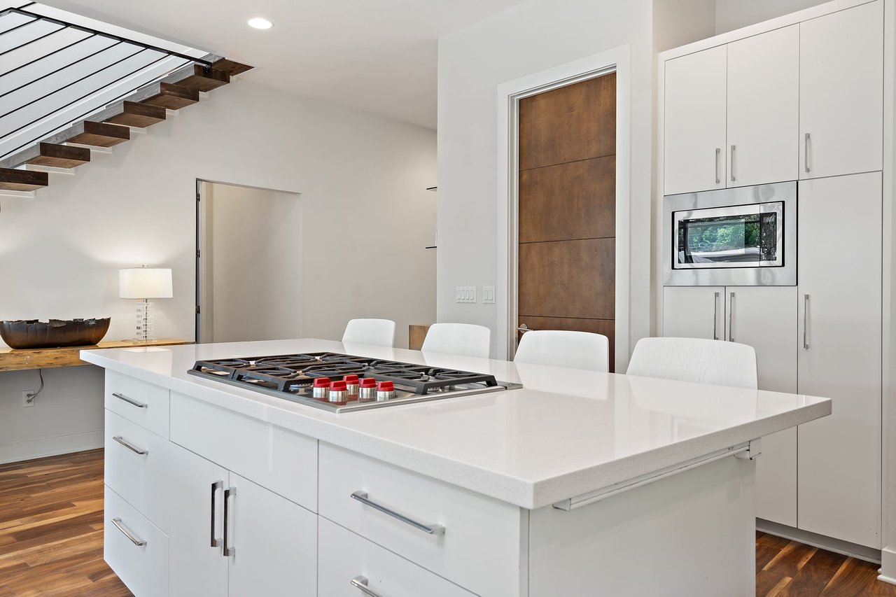 Kitchen island with a gas cooktop and white cabinetry at 34 Margranita Crescent, Tarrytown, Austin, TX.