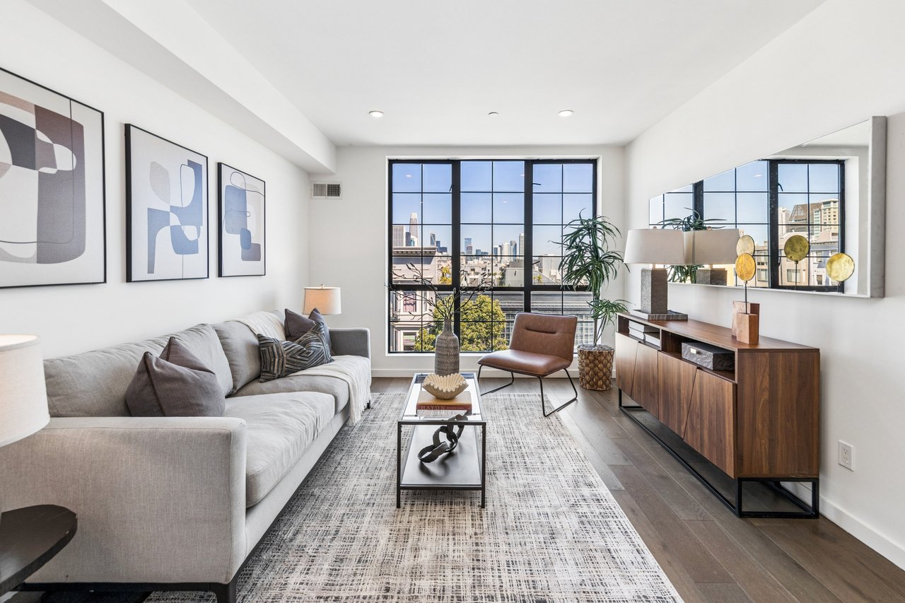 Light-filled living room with expansive floor-to-ceiling windows showcasing breathtaking city views, complemented by modern finishes and an open, airy layout perfect for both relaxing and entertaining.