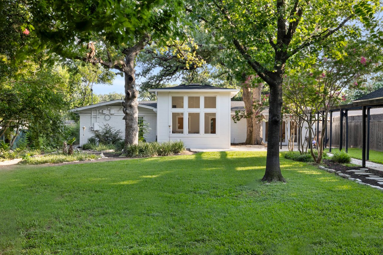Side yard with the home's modern addition and mature oak trees, Tarrytown, Austin.