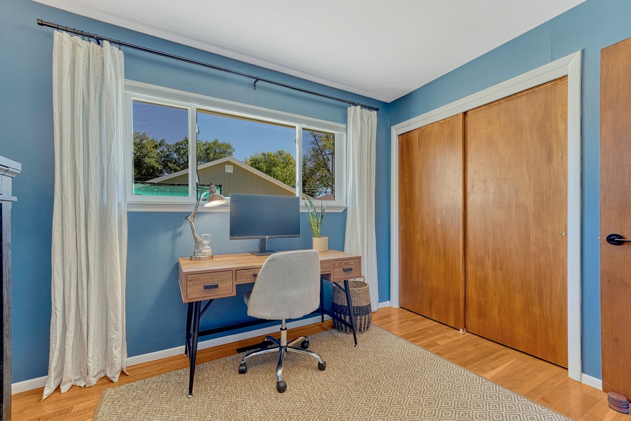 Main-level bedroom set up as an office, with hardwood floors and a double closet