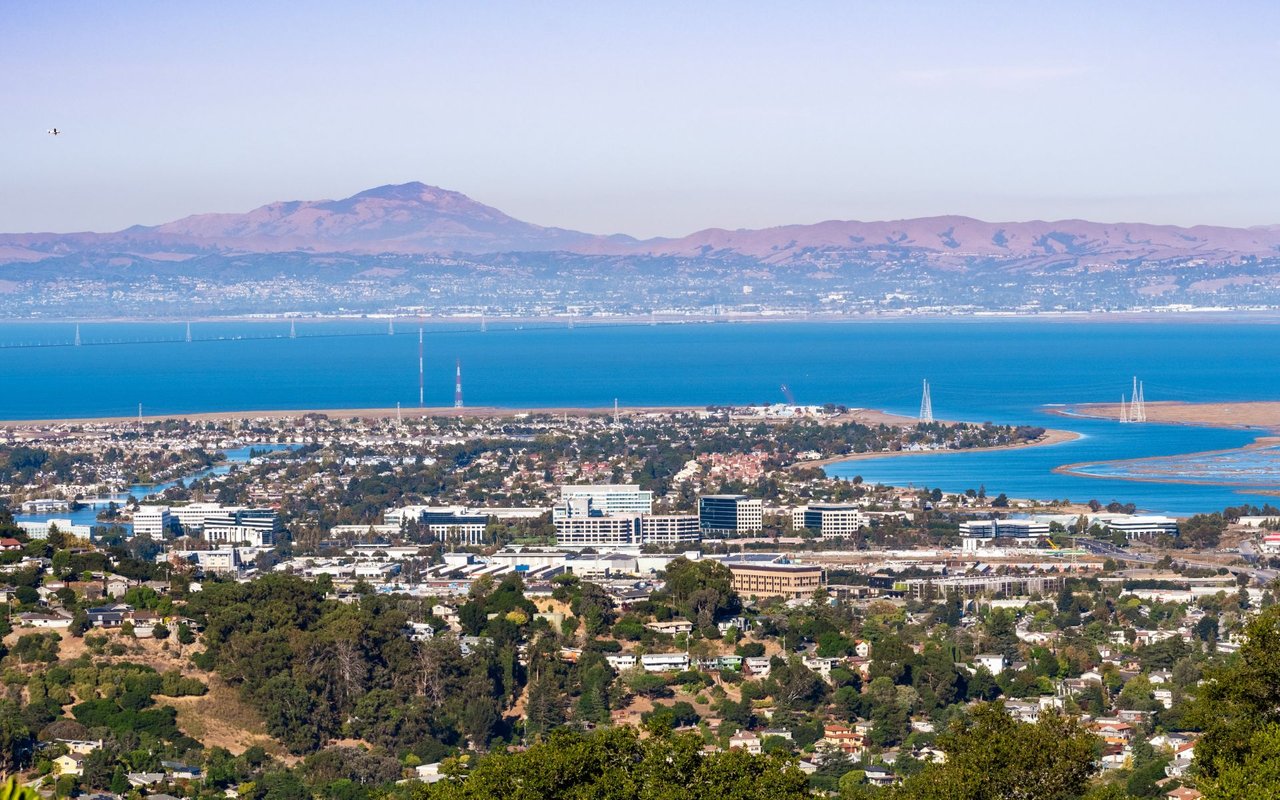 Bay Area city and shoreline wetlands beneath rolling hills across the bay.