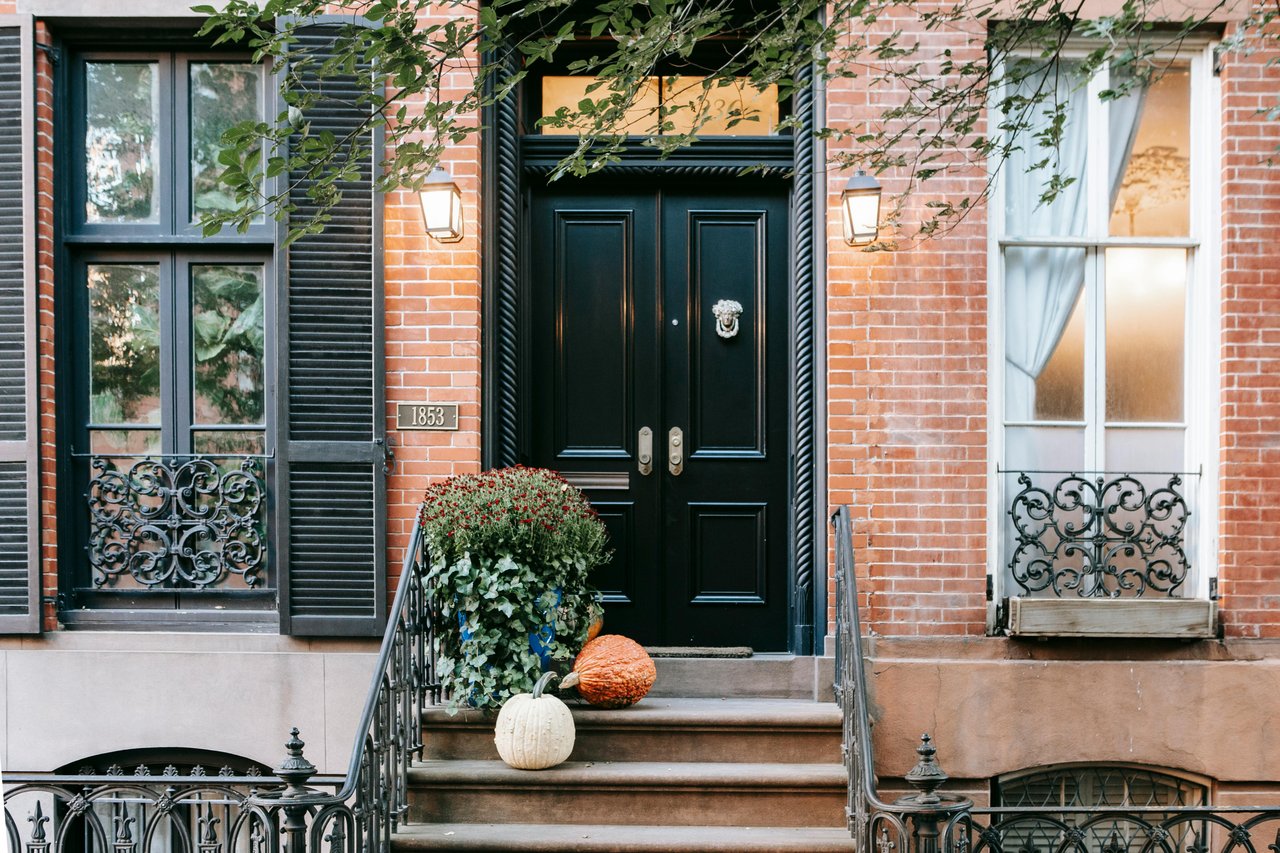 Front porch of a Main Line home featuring a double door, pumpkins and mums, inviting greenery, and classic architectural details.