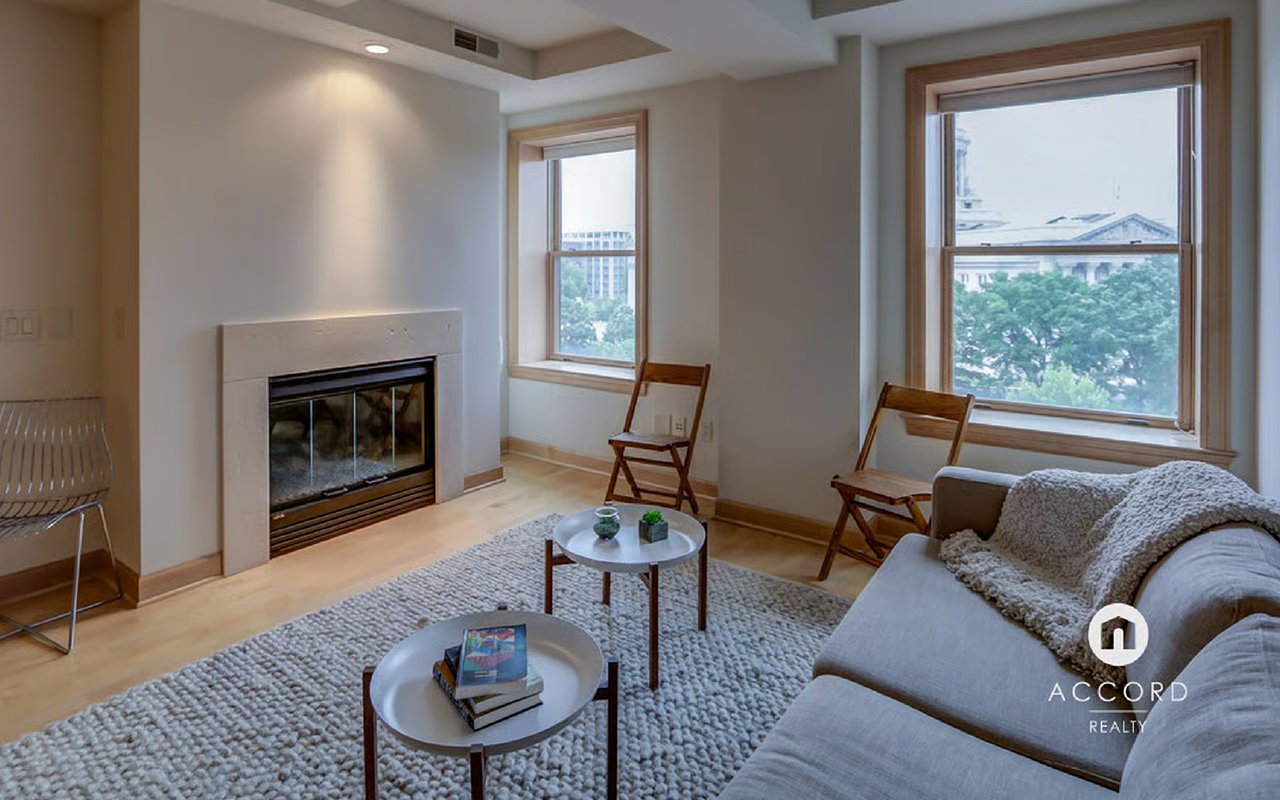 Living room with a fireplace and tall windows overlooking a capitol building.