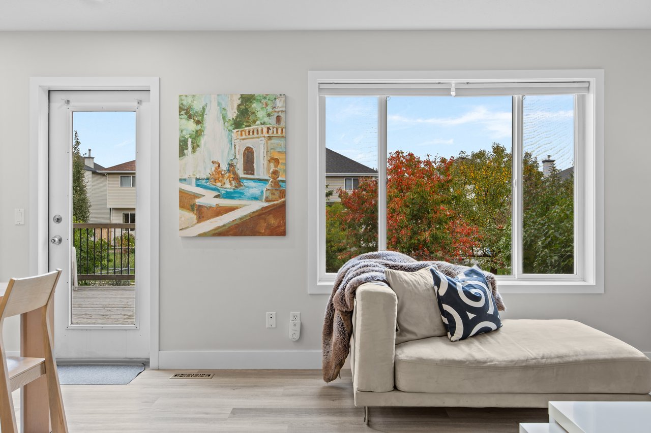 Living room with a cream chaise sofa and large window overlooking autumn foliage.