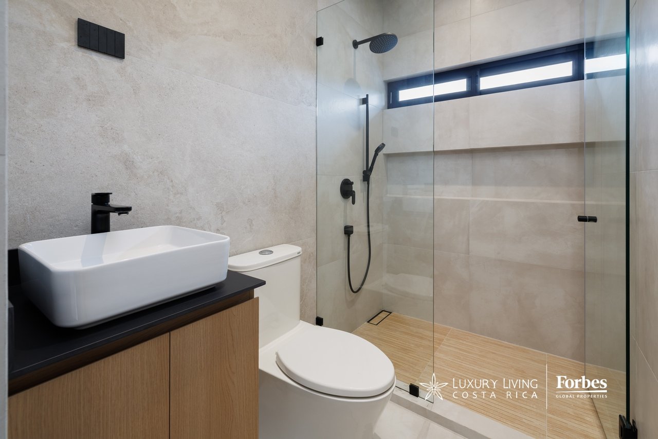 Modern bathroom with a glass walk-in shower, black fixtures, and a white vessel sink.