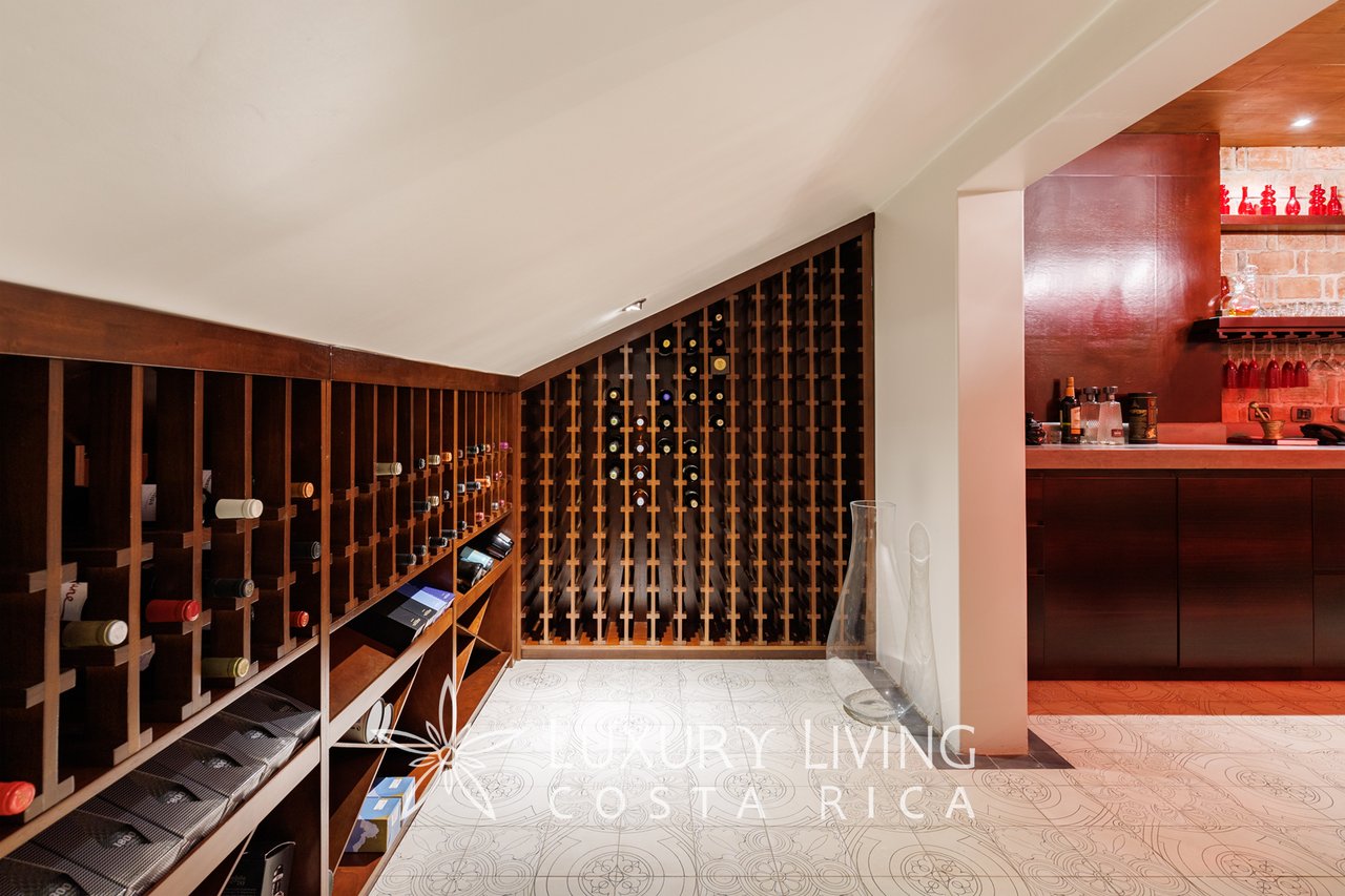 Wine cellar with floor-to-ceiling wooden wine racks and an adjoining bar.
