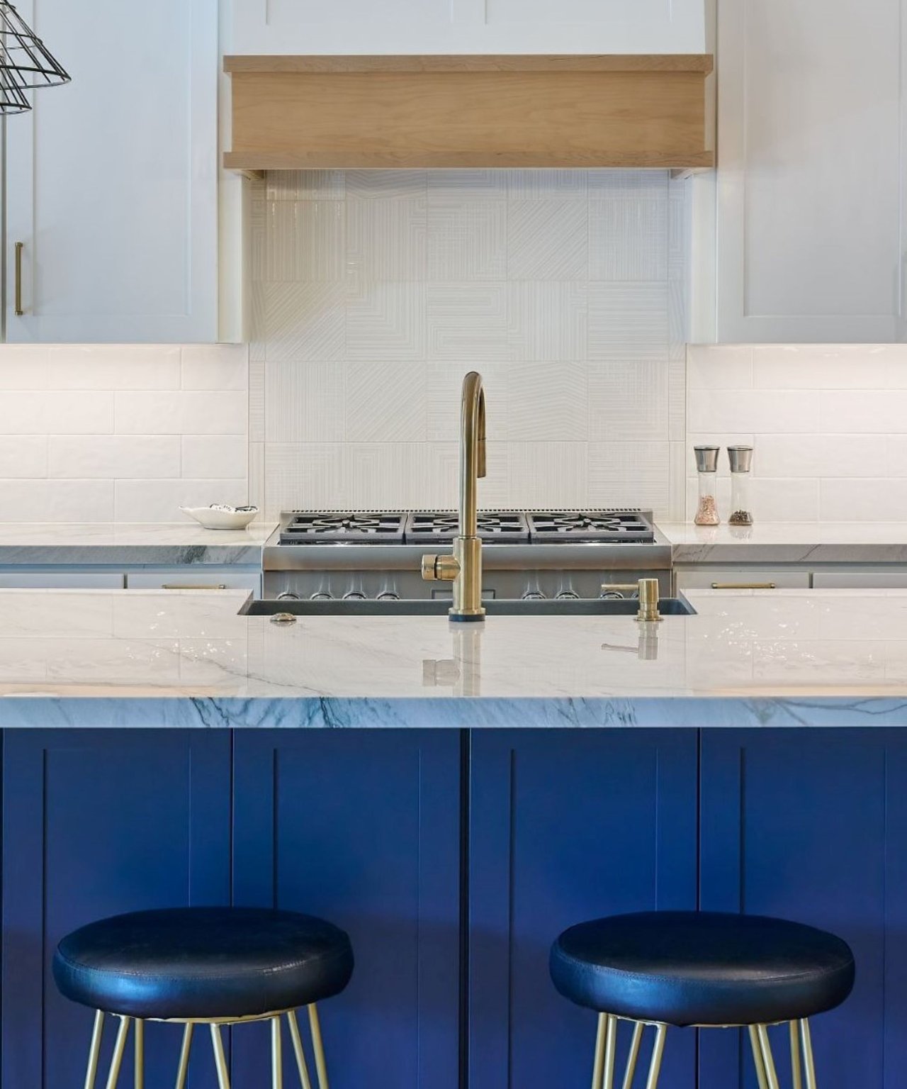 Custom kitchen in Naples home with blue cabinetry, marble countertops, and gold faucet