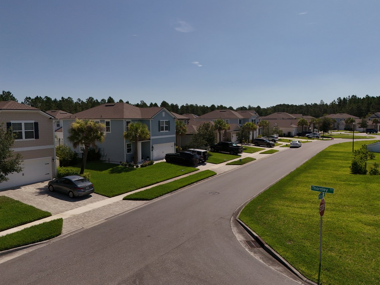 Aerial view of Hartford Silverleaf homes along a curving street lined with lawns and palm trees.