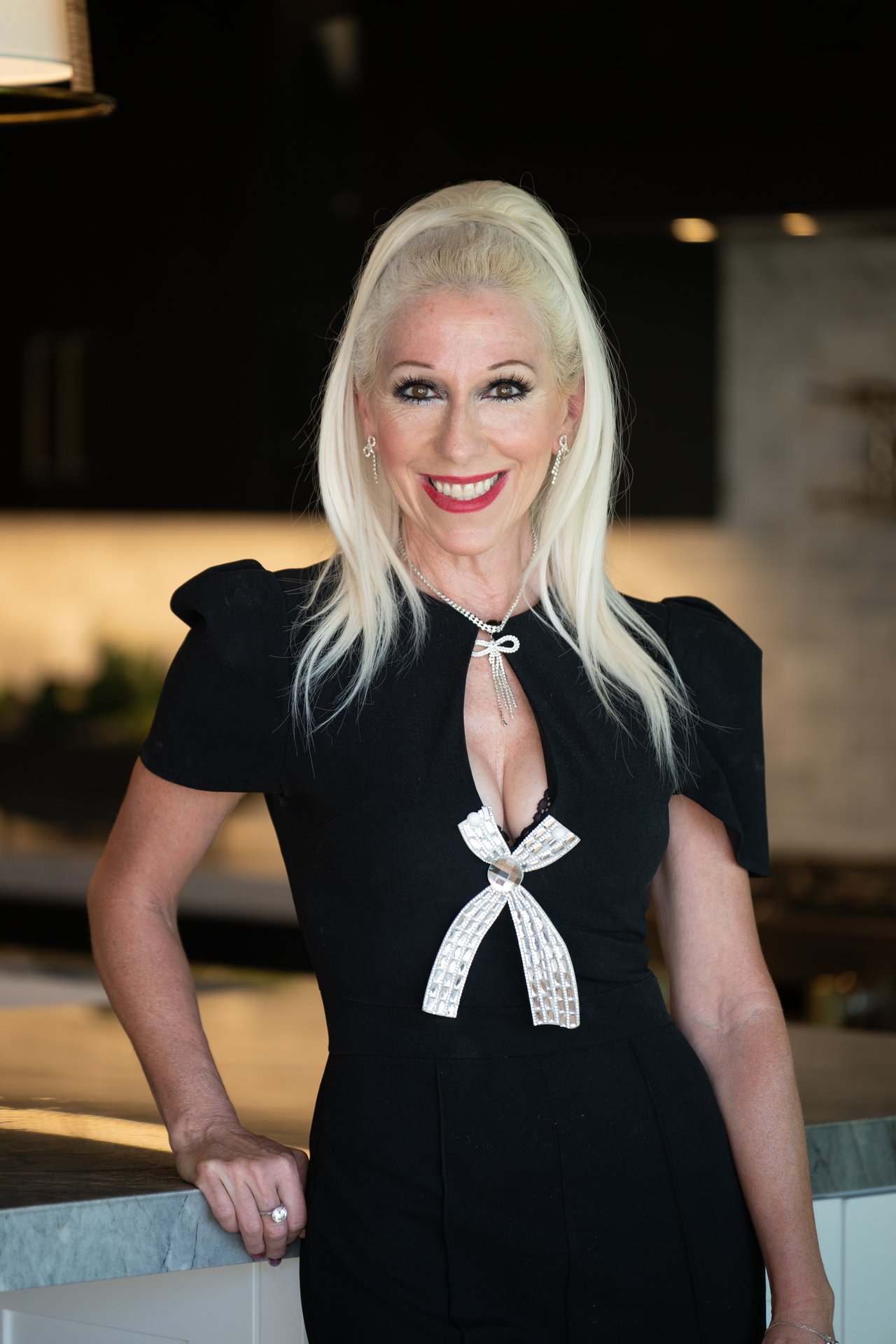 Tiffany Williams, realtor, smiling in a black dress with a jeweled bow.