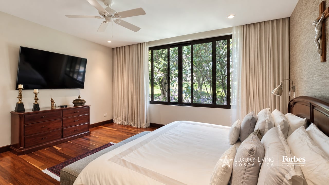 Bedroom with a large white bed and wide garden-facing window.