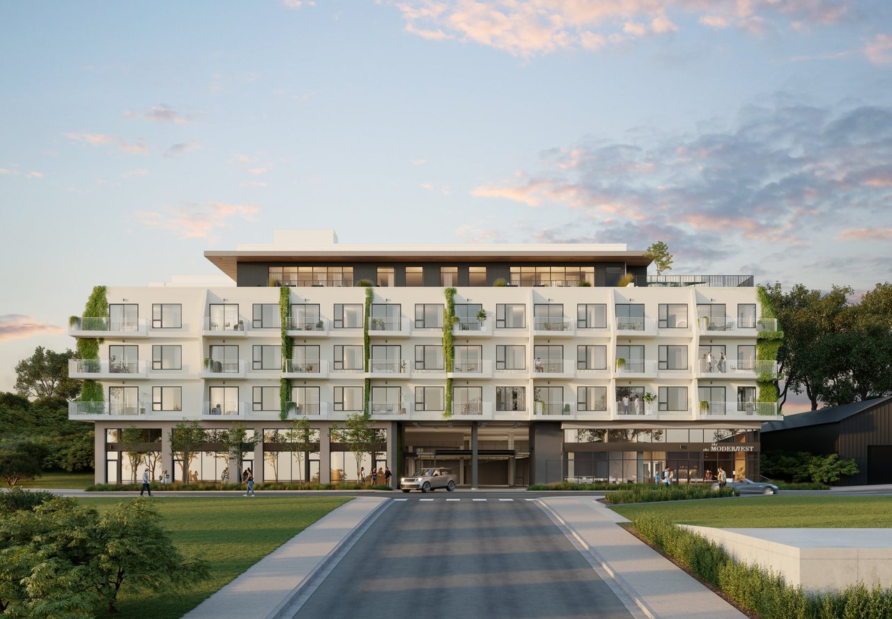 The Modernest residential building with landscaped balconies and a rooftop level at dusk.