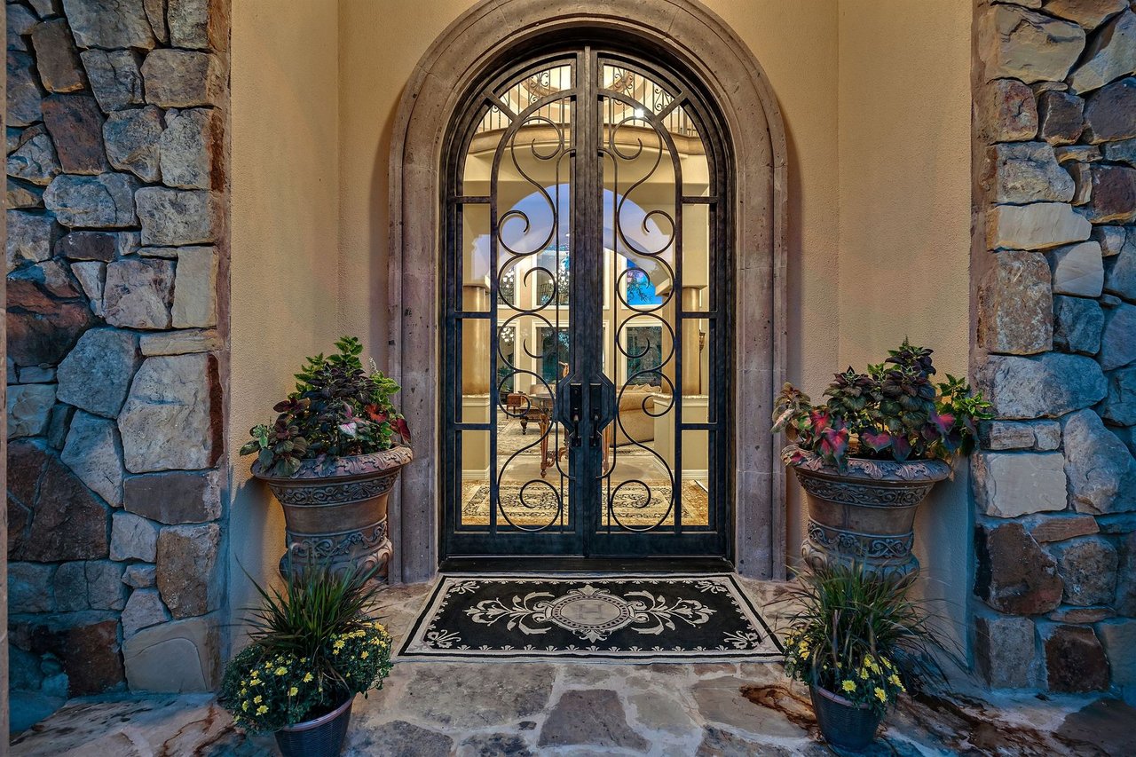 Detail of the arched iron and glass front door with a stone surround at 25715 Cliff Circle, Lakecliff on Lake Travis, Spicewood, Texas.
