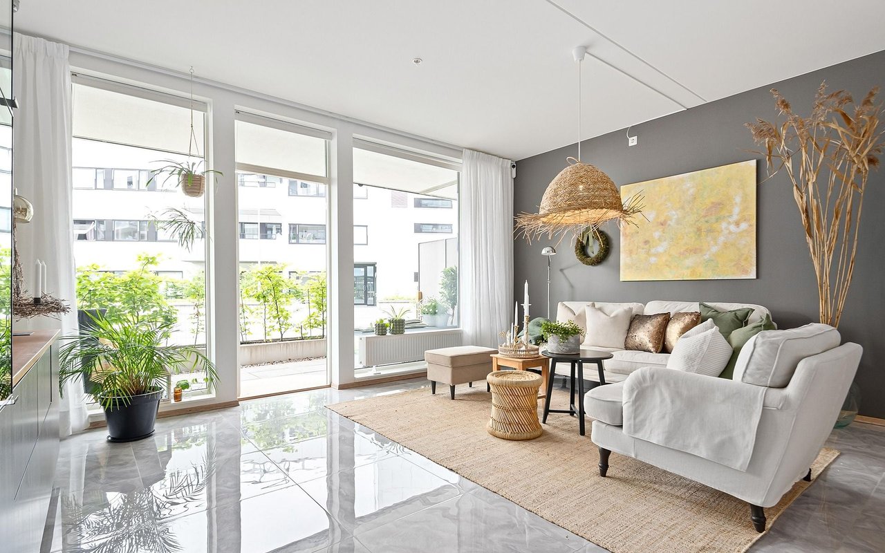 Bright living room with a white sectional, gray accent wall, and floor-to-ceiling windows.