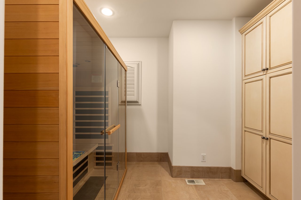 Home sauna with a glass-fronted wooden enclosure and tall built-in cabinets.
