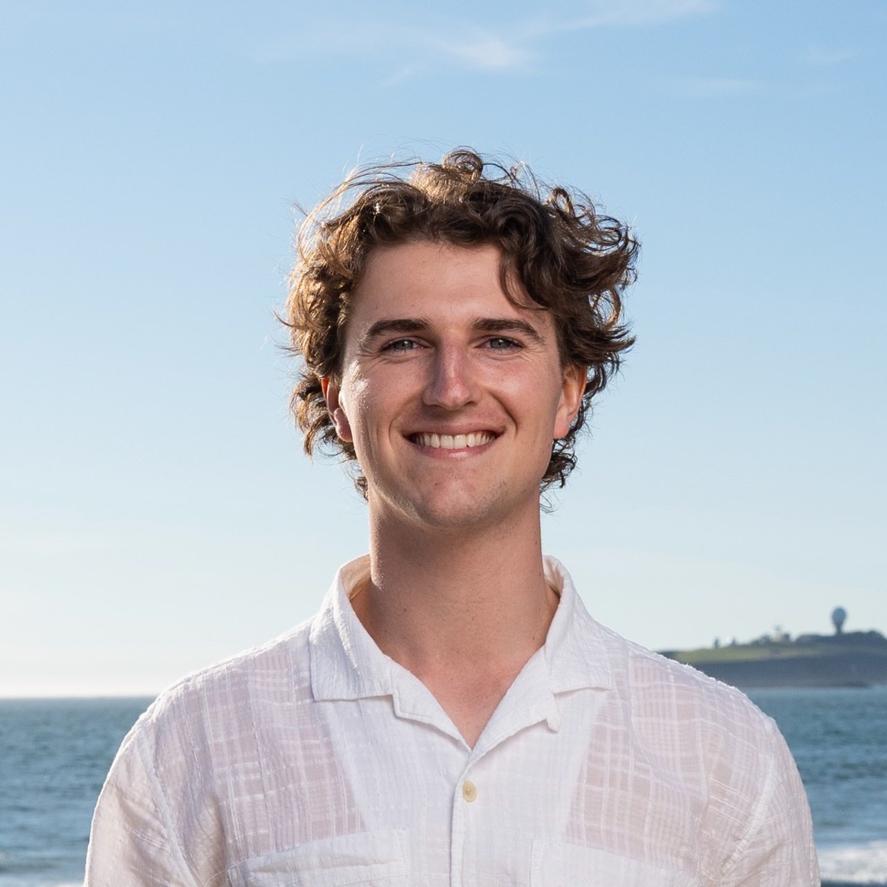 Parker Nishkian, real estate agent with Ocean Element Real Estate, standing on a beach in Half Moon Bay along the San Mateo County Coastside