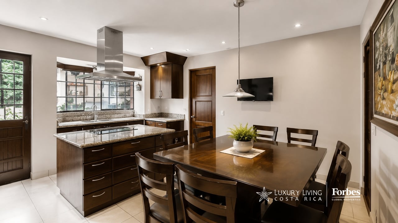 Kitchen and dining area with a granite island, dark wood cabinetry, and a large dining table.