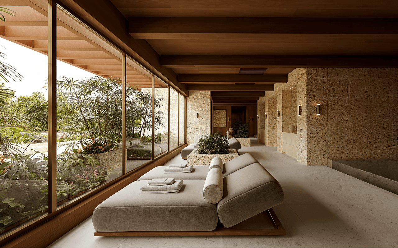 Furnished lounge with cream sofas, stone walls, and floor-to-ceiling windows overlooking tropical landscaping.