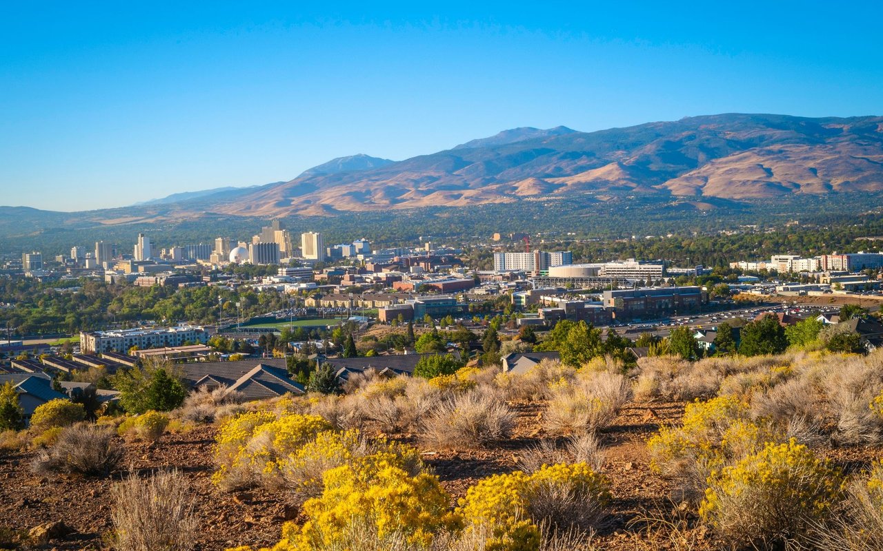 Panoramic view of Reno’s skyline and neighborhoods beneath the surrounding mountains.