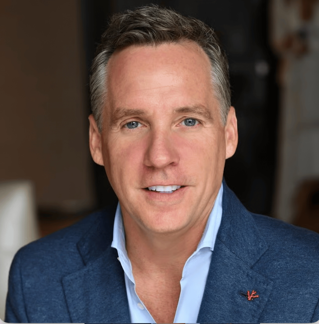 Michael Passaro in a navy blazer and light blue shirt with a red lapel pin.