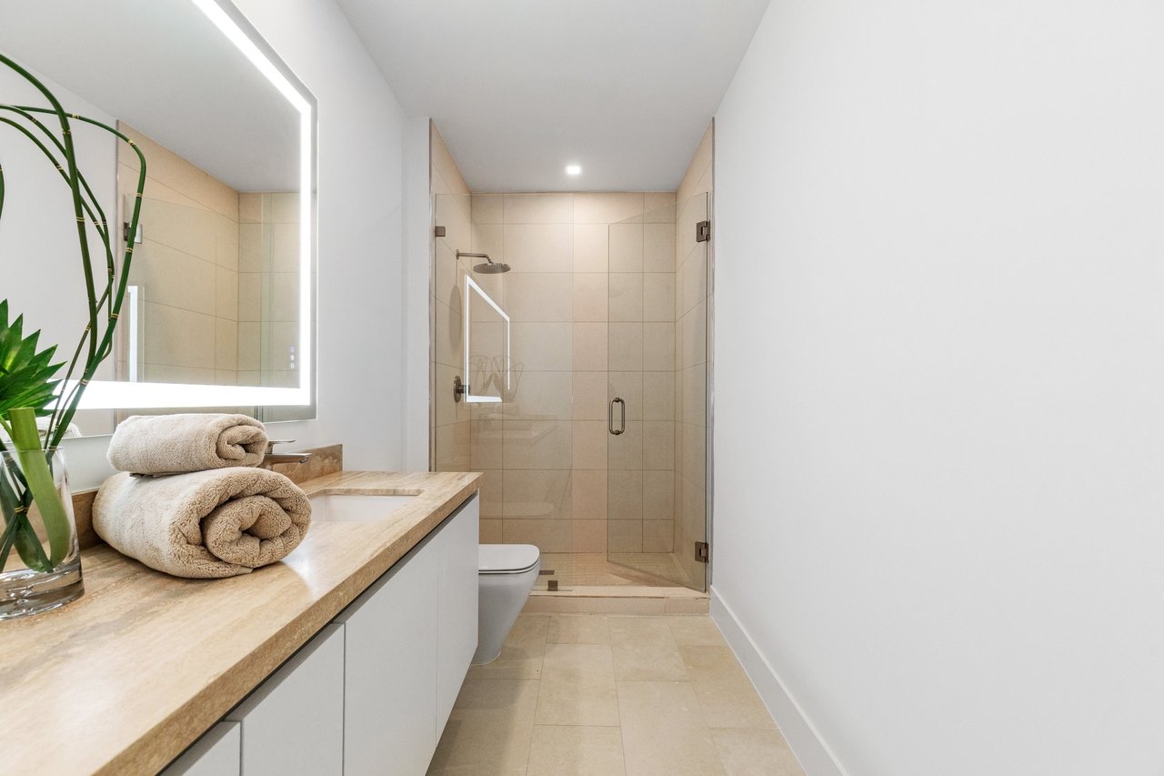 Arbor Coconut Grove residence bathroom with glass shower and illuminated mirror