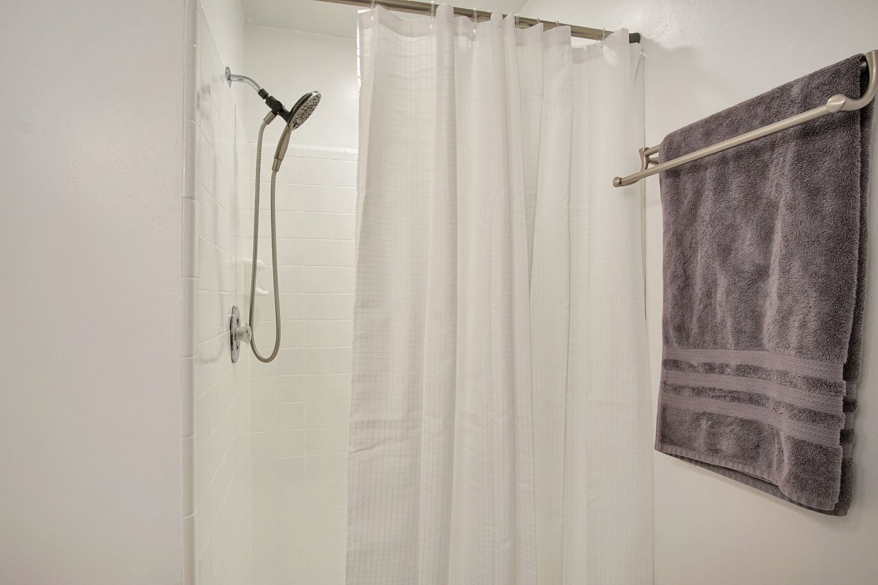 A modern shower featuring a sleek shower head and a neatly hung towel nearby.