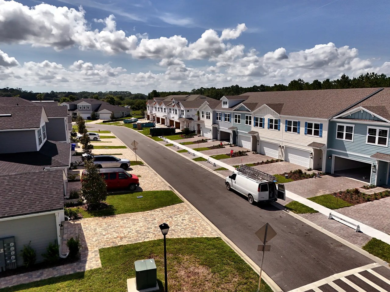 Aerial view of a townhome street with attached homes and parked vehicles.