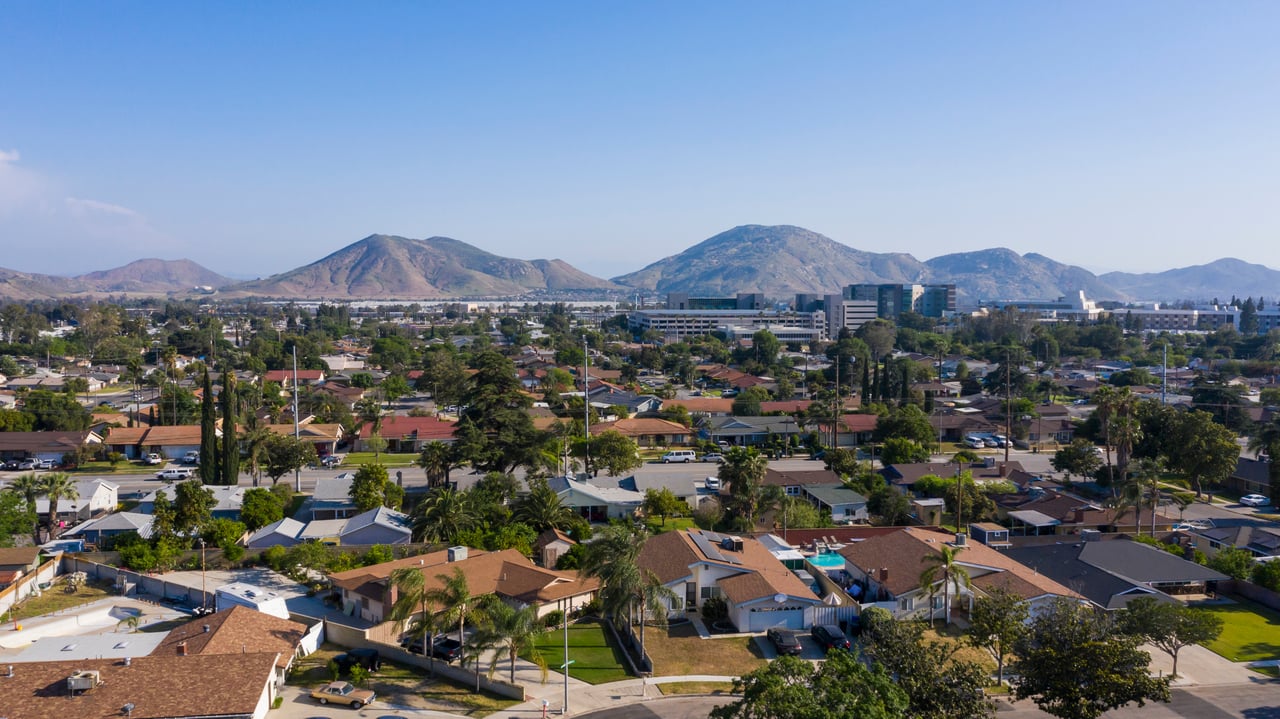 Aerial view of homes and tree-lined streets with mountains in the distance.