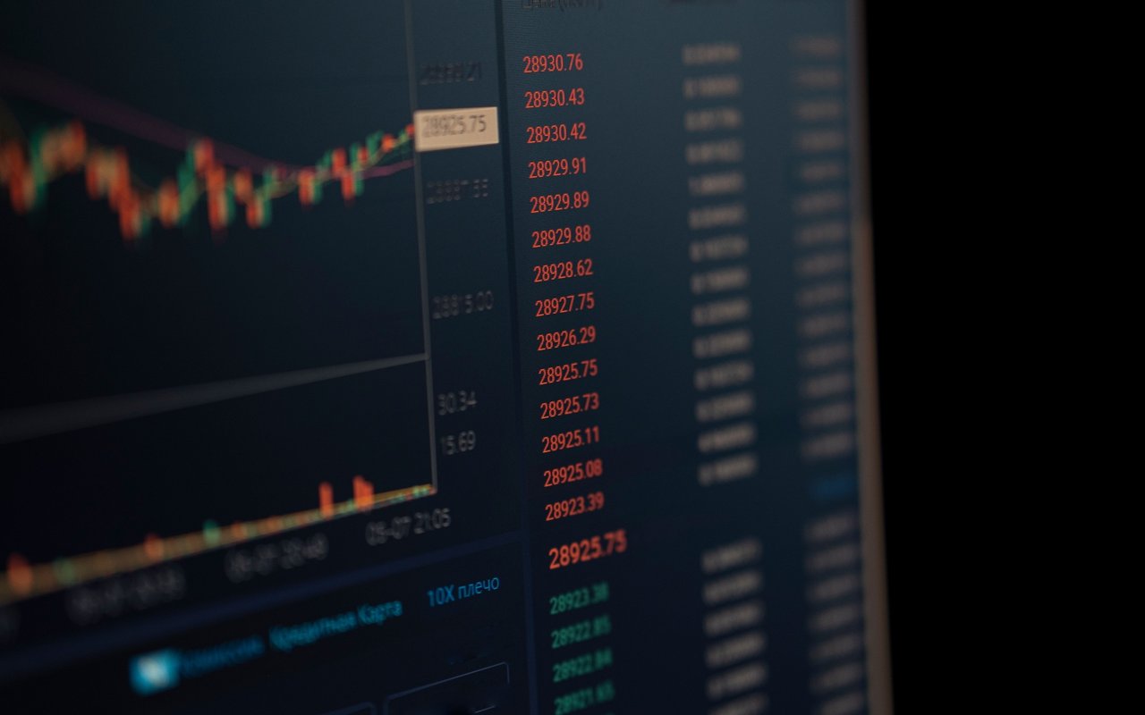 Trading screen with fluctuating market charts and red and green price figures.