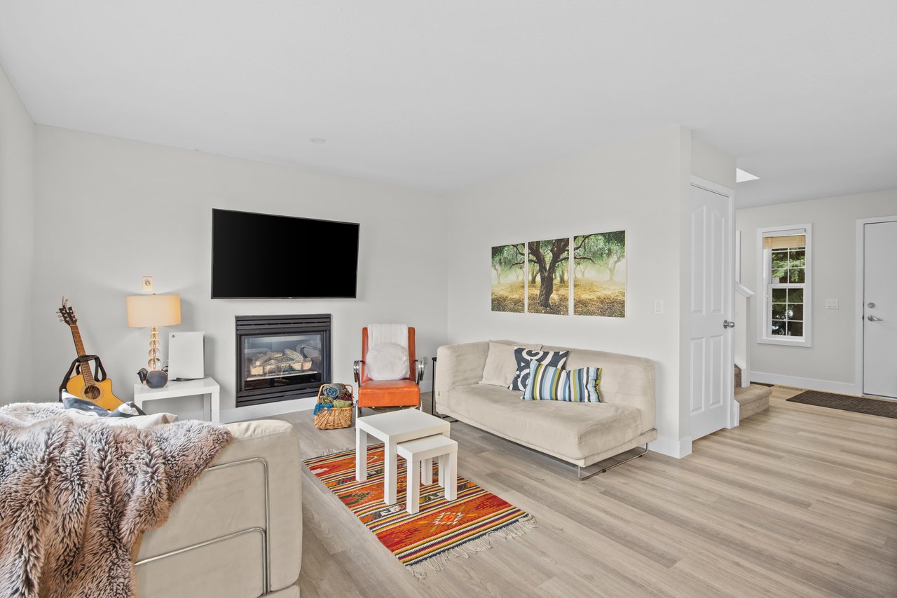Living room with a gas fireplace, cream sofas, and a colorful striped rug.