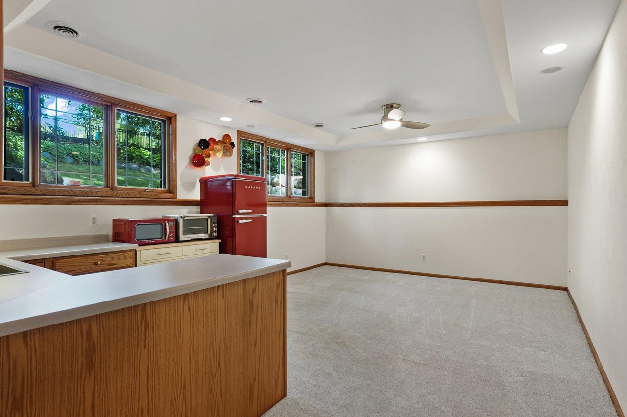 A finished basement with carpet, a kitchenette, and large windows in a Madison-area home, the kind of space that is costly to repair after a water backup.