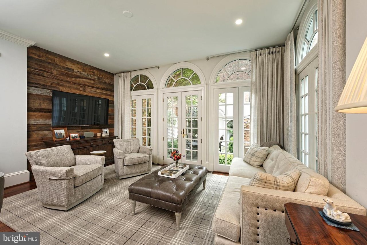 Living room with arched French doors, pale seating, and a reclaimed-wood television wall.