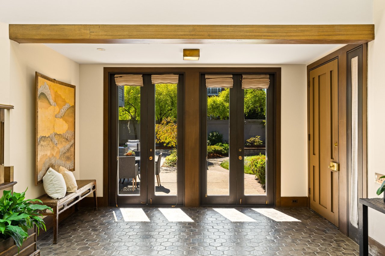 Entryway with dark-framed glass doors opening onto a landscaped garden.