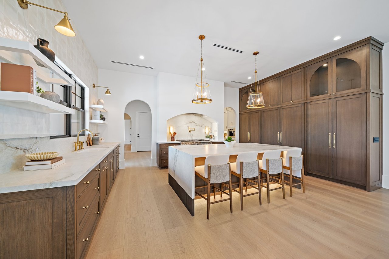 Kitchen with a large stone island, dark wood cabinetry, and brass pendant lights.