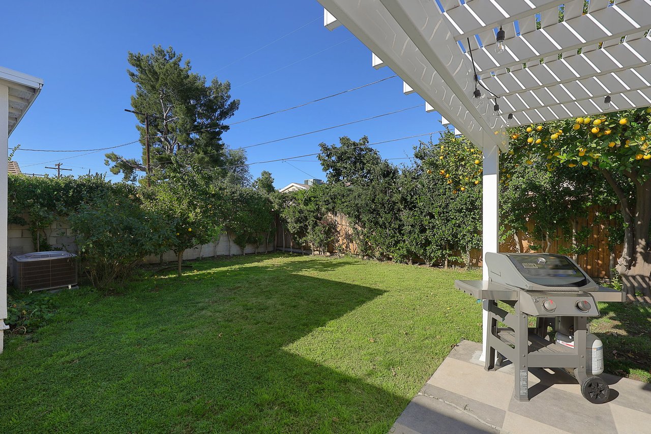 Side patio with barbecue grill, string-lit pergola, and fenced yard at 17049 Baltar Street