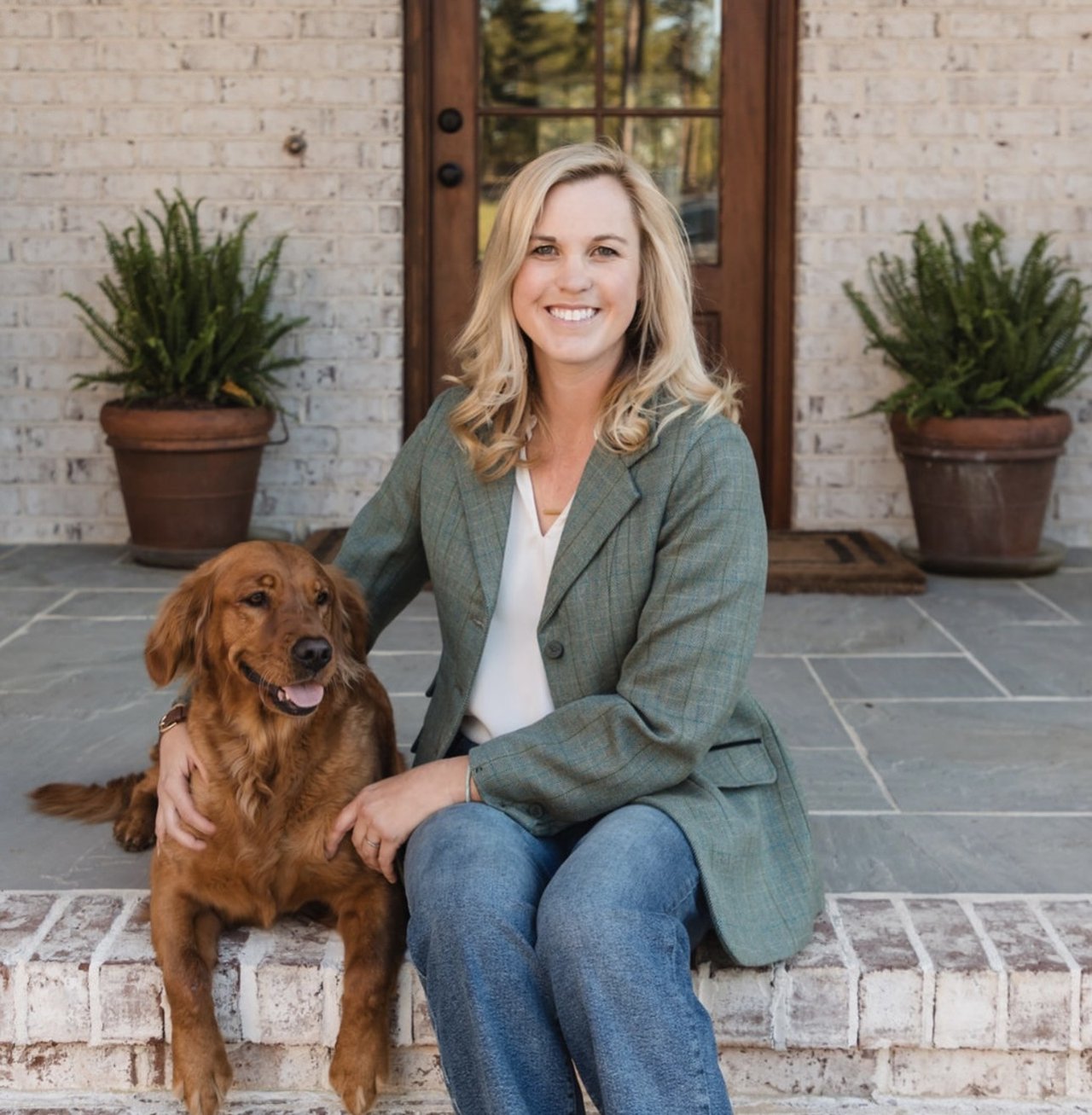 Brittany Paschal seated beside a golden retriever on a brick porch.