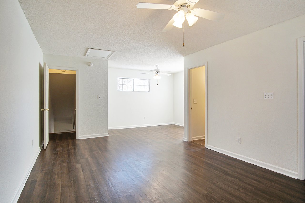 An empty room featuring hardwood floors and pristine white walls, creating a bright and spacious atmosphere.