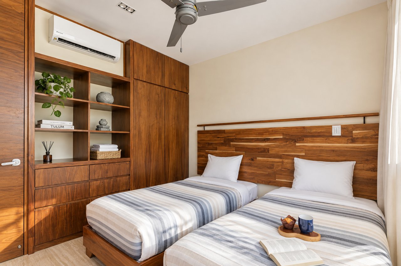 Bedroom with two single beds, striped bedding, and warm wood built-ins.